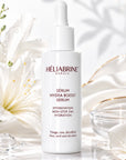 Sérum Hydra-Boost Héliabrine 30 ml, flacon compte-gouttes blanc posé près d'un lys