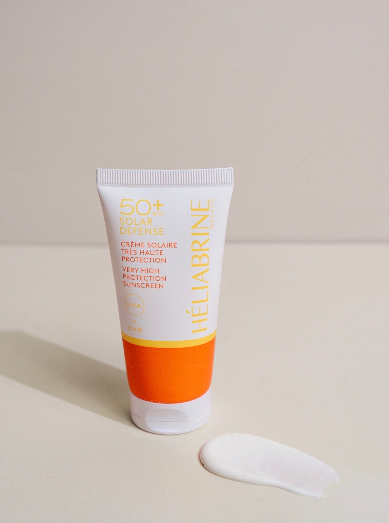 Texture blanche de la crème solaire SPF 50+ Héliabrine déposée à côté du tube